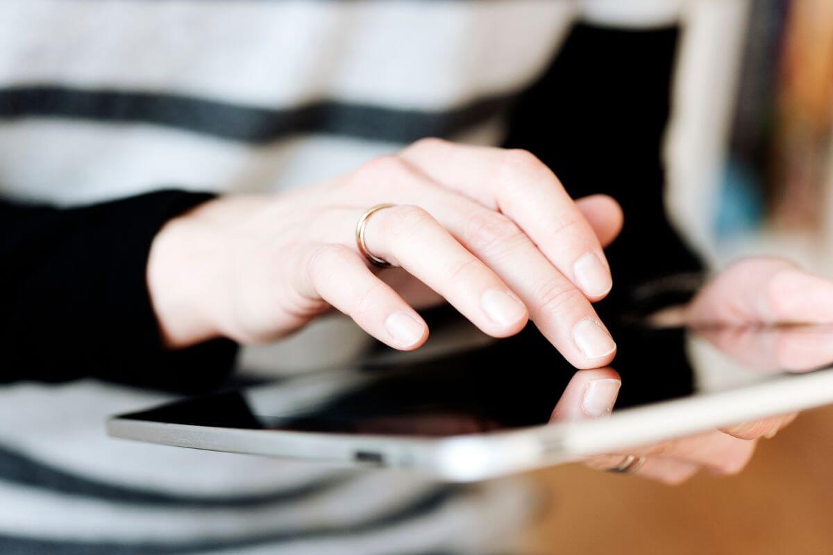 The picture of a girl's hand using a tablet to review subscriptions and recurring bills can free up money for what matters.