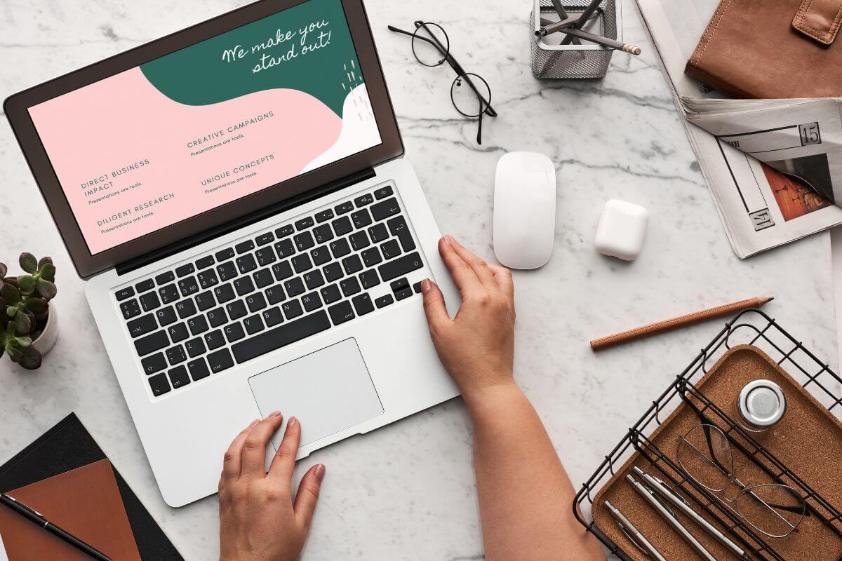The picture tells about an eyeglass, a pen, an ear pod, magazines, a container with stuff, and a girl's hand using a laptop with a screen display indicating to create and sell digital products on Etsy that can generate passive income once uploaded.