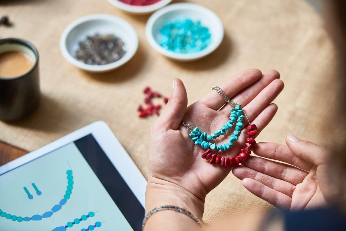 The hot shows a coffee, a wile small bowl with gems, a tablet, and a girl holding bracelets which means to sell handmade craft allows you to turn hobbies into income.
