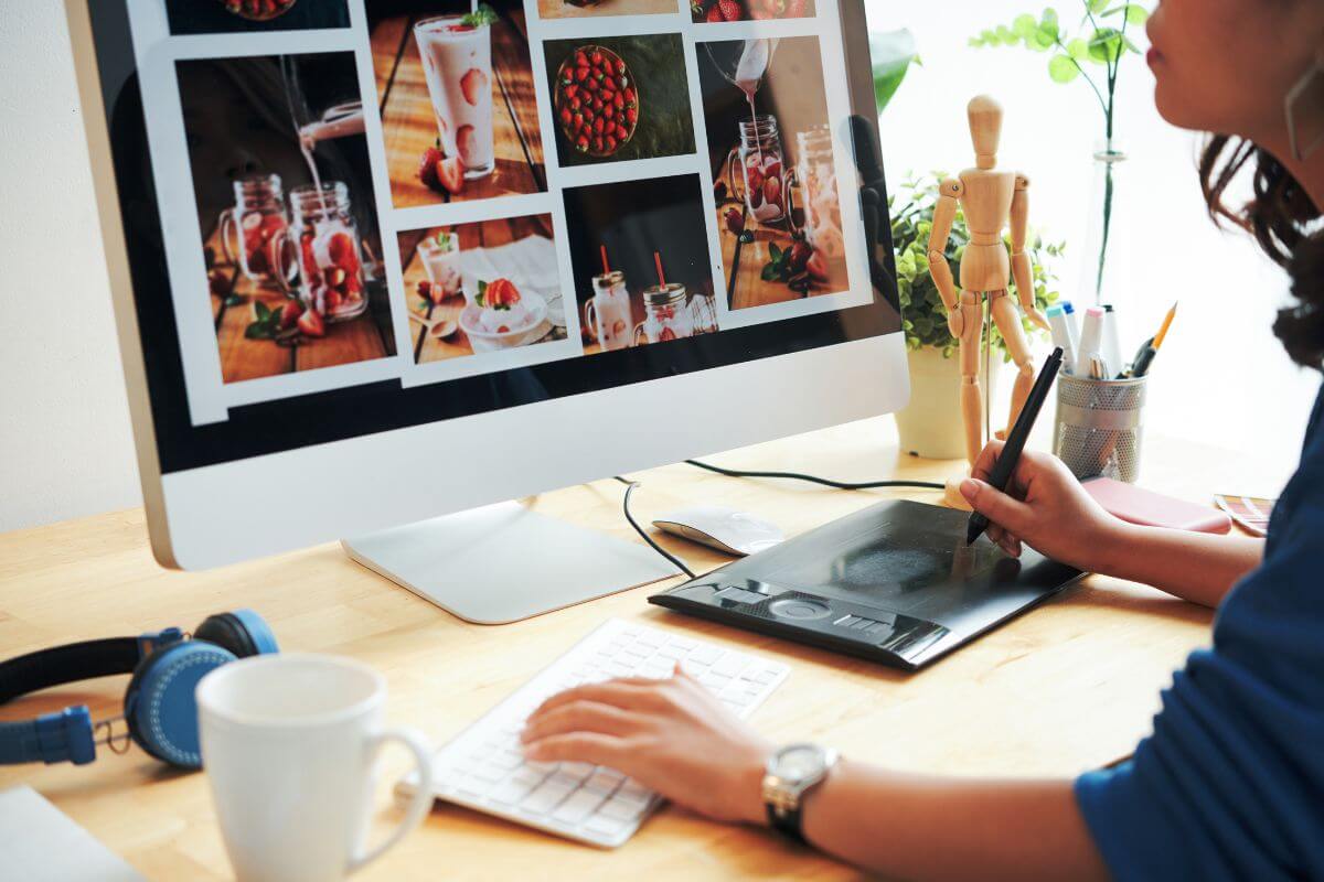 The image shows a headset, a coffee, pens, a human wooden figure, plants, and a girl editing the images on the computer which refers to selling stock photos to earn a passive income stream if you have a good eye for visuals.
