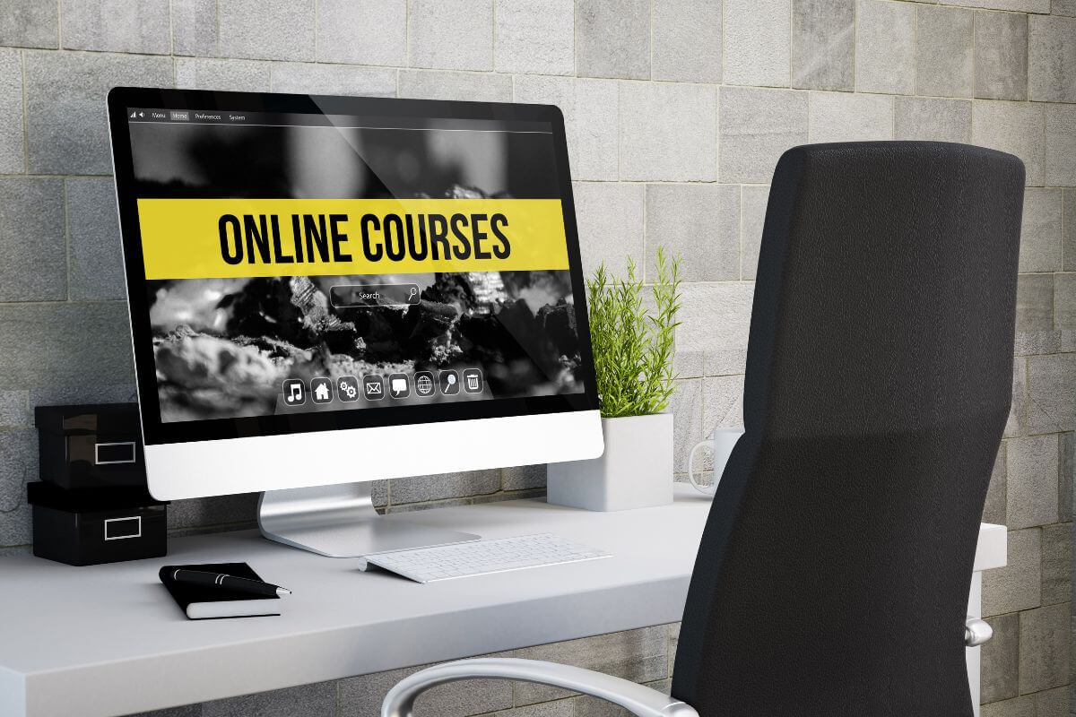 The photo shows a chair, a plant, a notebook, a pen, and a monitor with a screen display referring to creating an online course that can generate passive income with a long-term earning potential.
