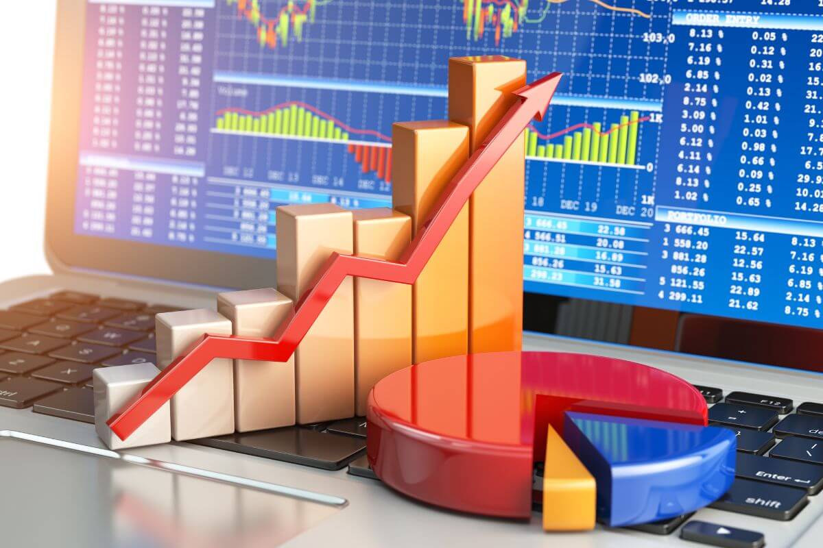 The photo of visual graphs and a laptop with graphs and numbers on the screen refers to learning to trade stocks that can turn into a reliable income stream.