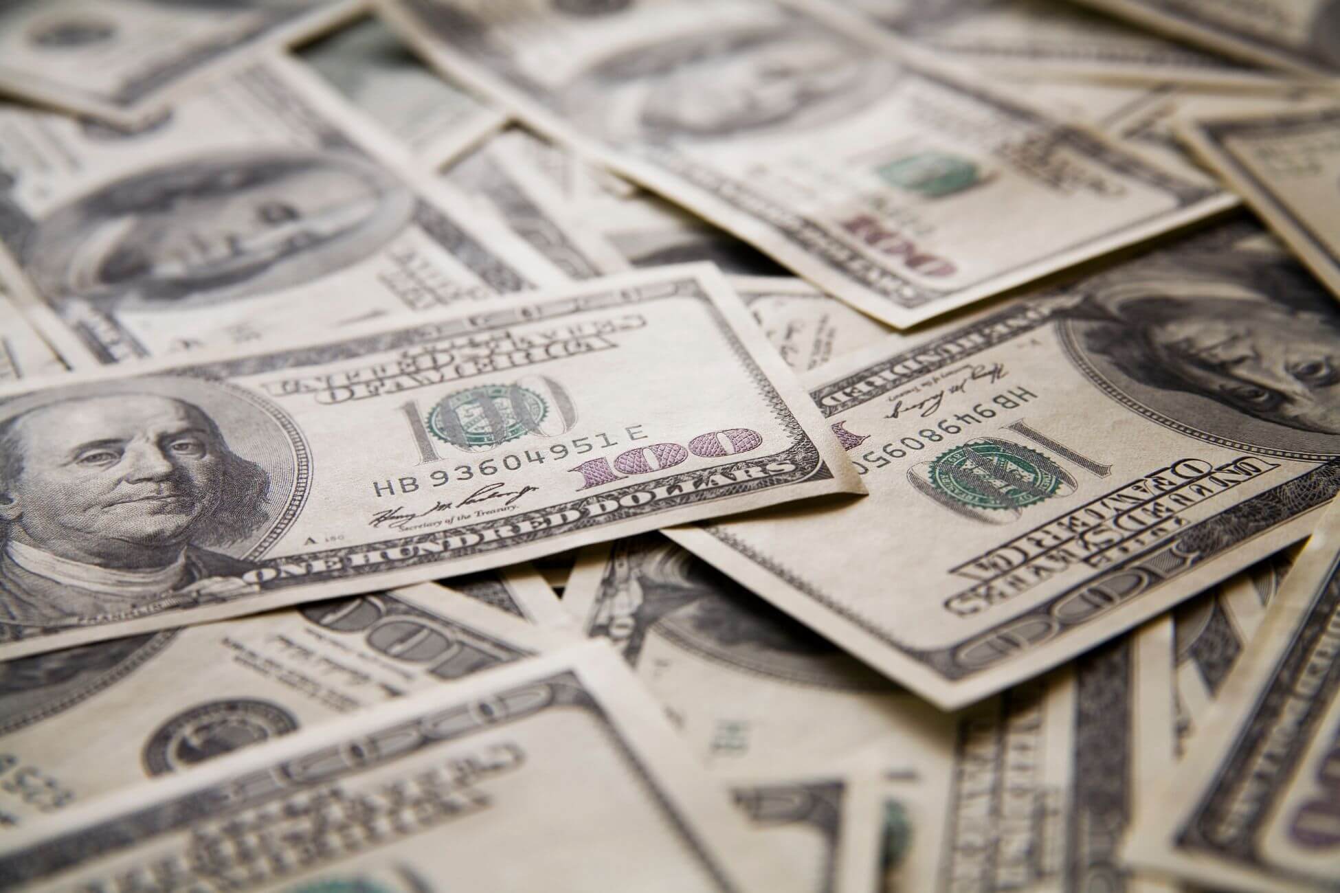 The image shows dollar bills scattered referring to why saving your first 100k gives you freedom that giving you options and peace of mind.