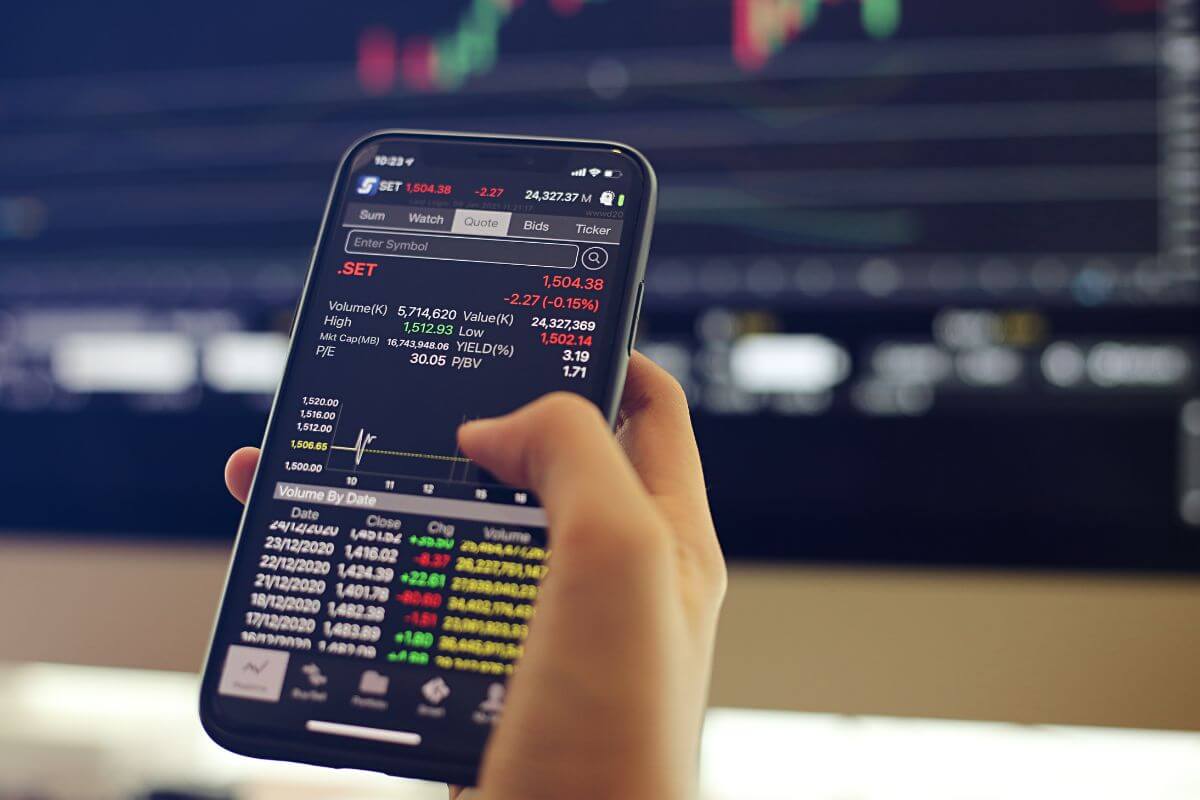 The picture shows a man's hand using a phone referring to trade options that can bring in quick cash and a way to grow their income.