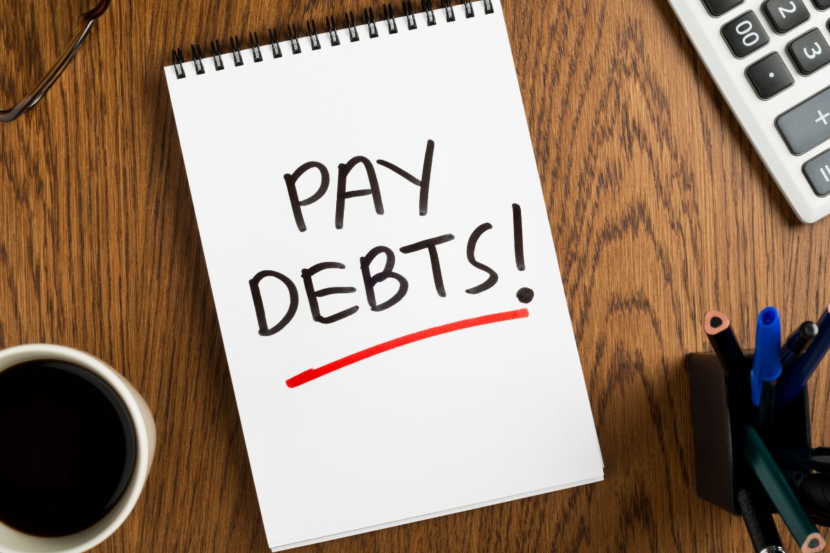 Image of a notebook with pay debts wording.