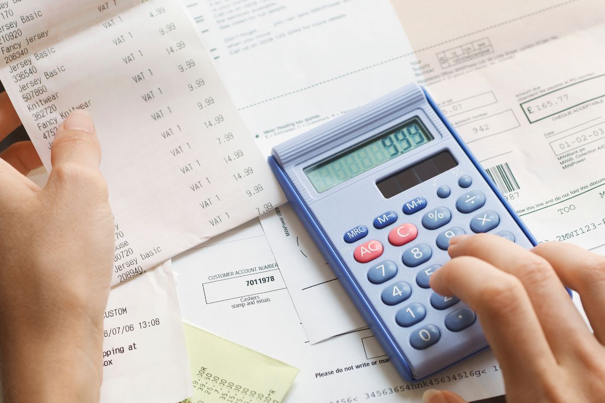 A woman's hand calculating expenses.