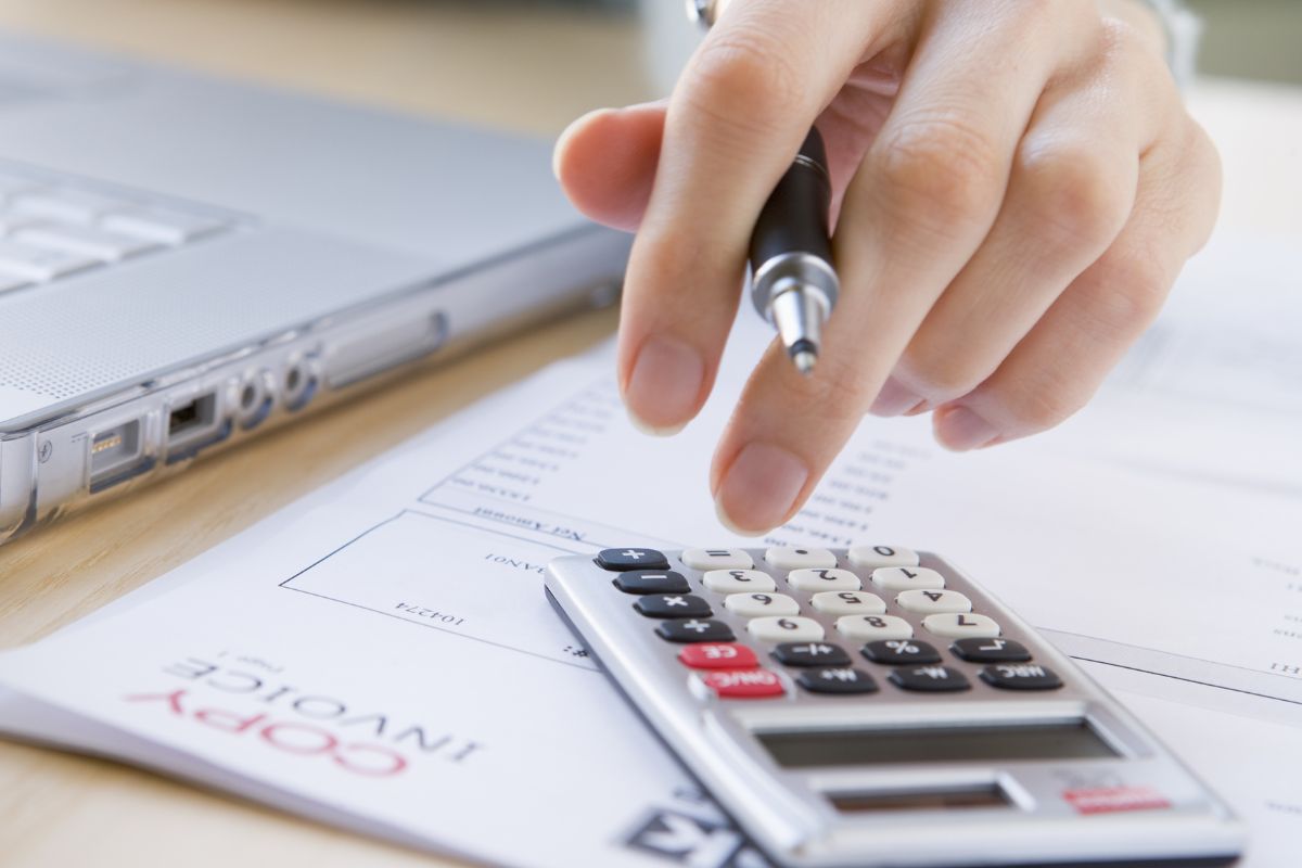 A woman's hand calculating bill payments.