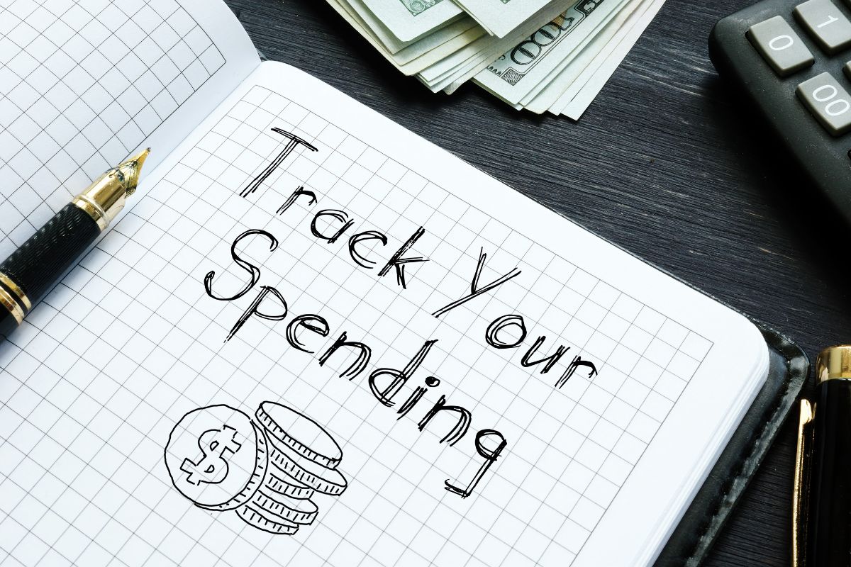The image shows a notebook with track your spending wording.