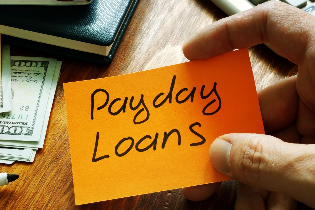A man's and holding a paper with payday loan wording.