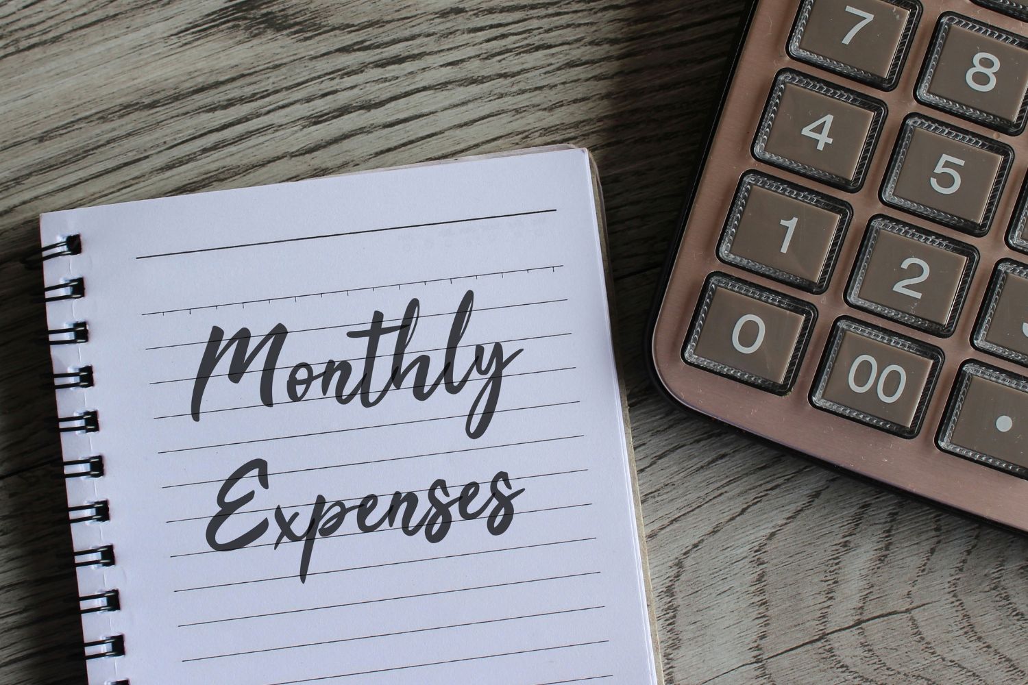 A calculator and a notebook with monthly budget wording.