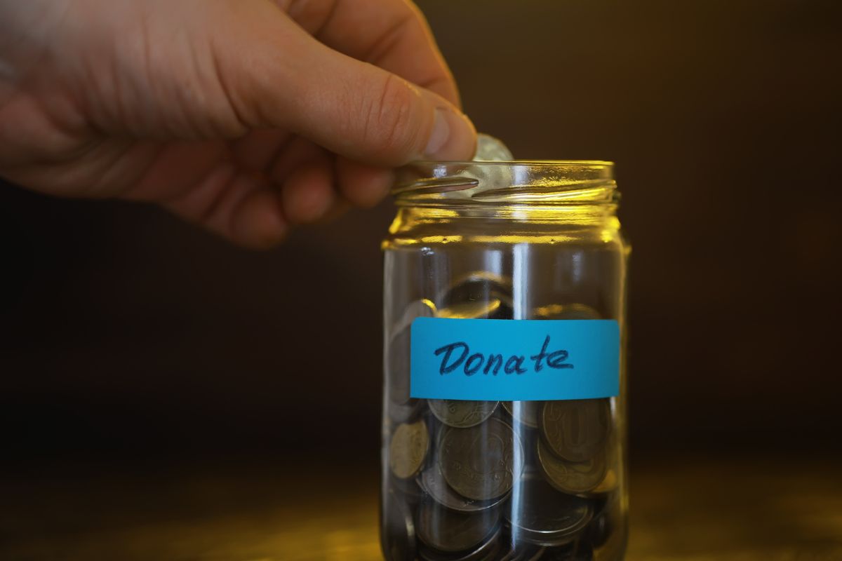 A man's hand saving donation money.