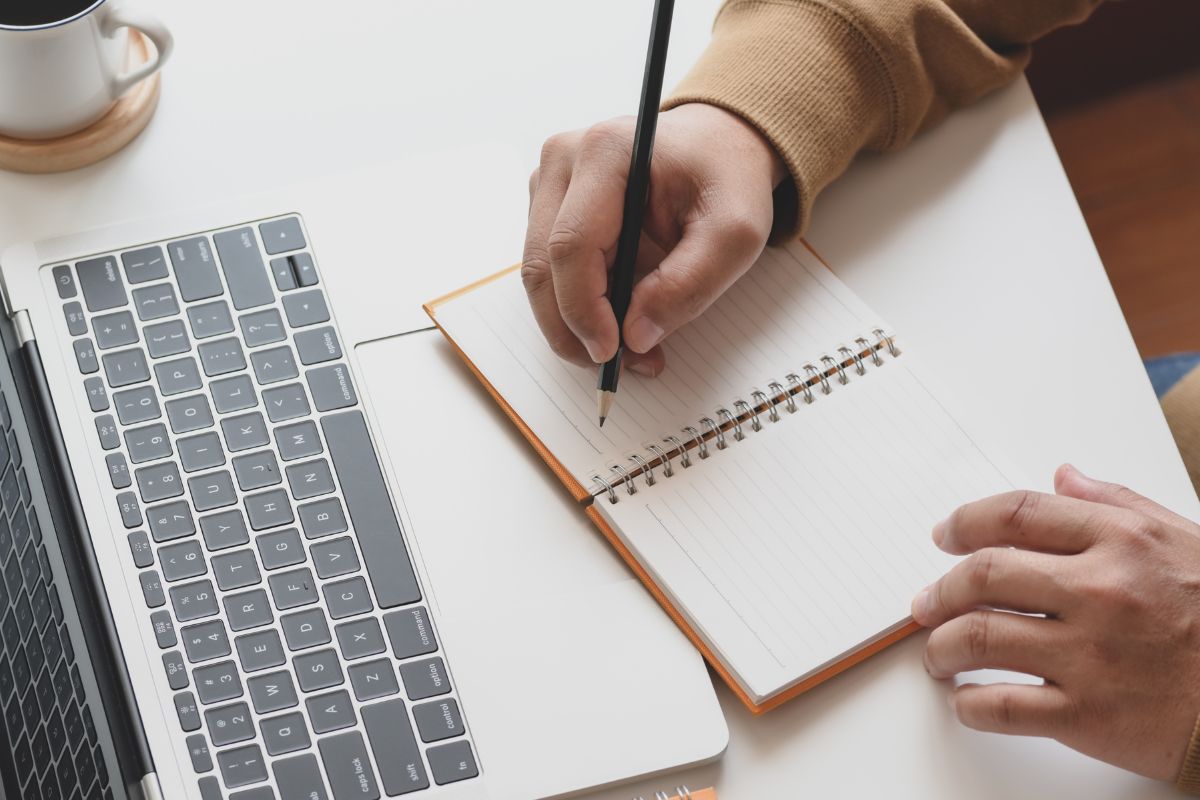 A man writing on a notebook.