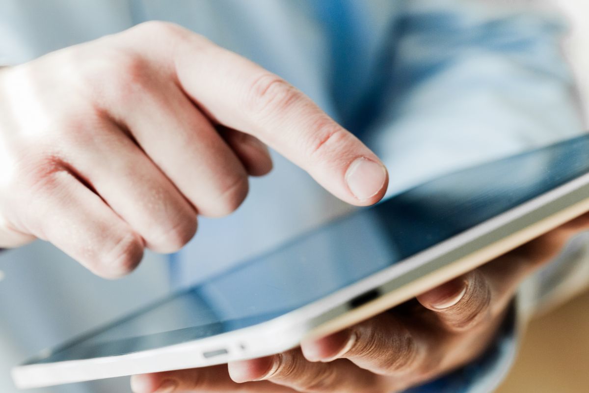 Image of a man's hand using a tablet device.
