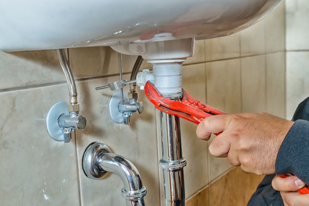 The image shows a man's hand repairing a plumber.