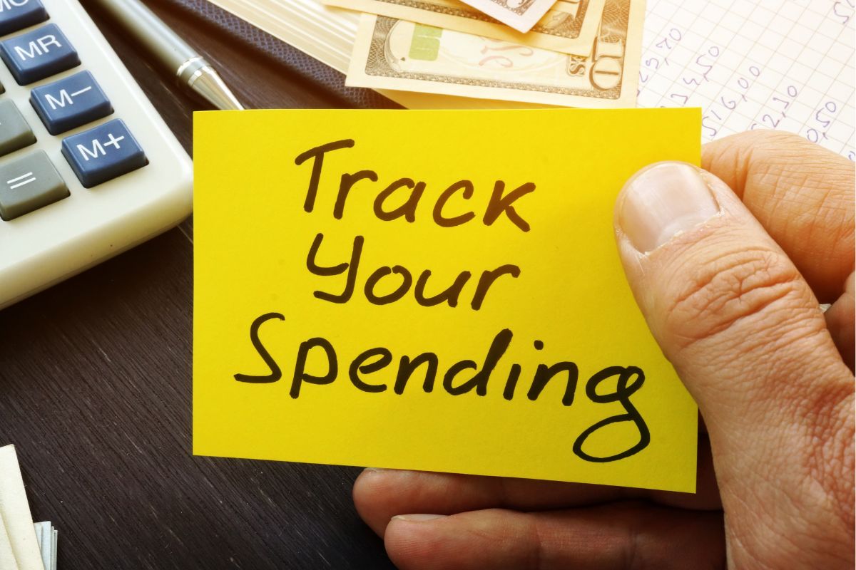 A man's hand holding a paper with Track your Spending wording.