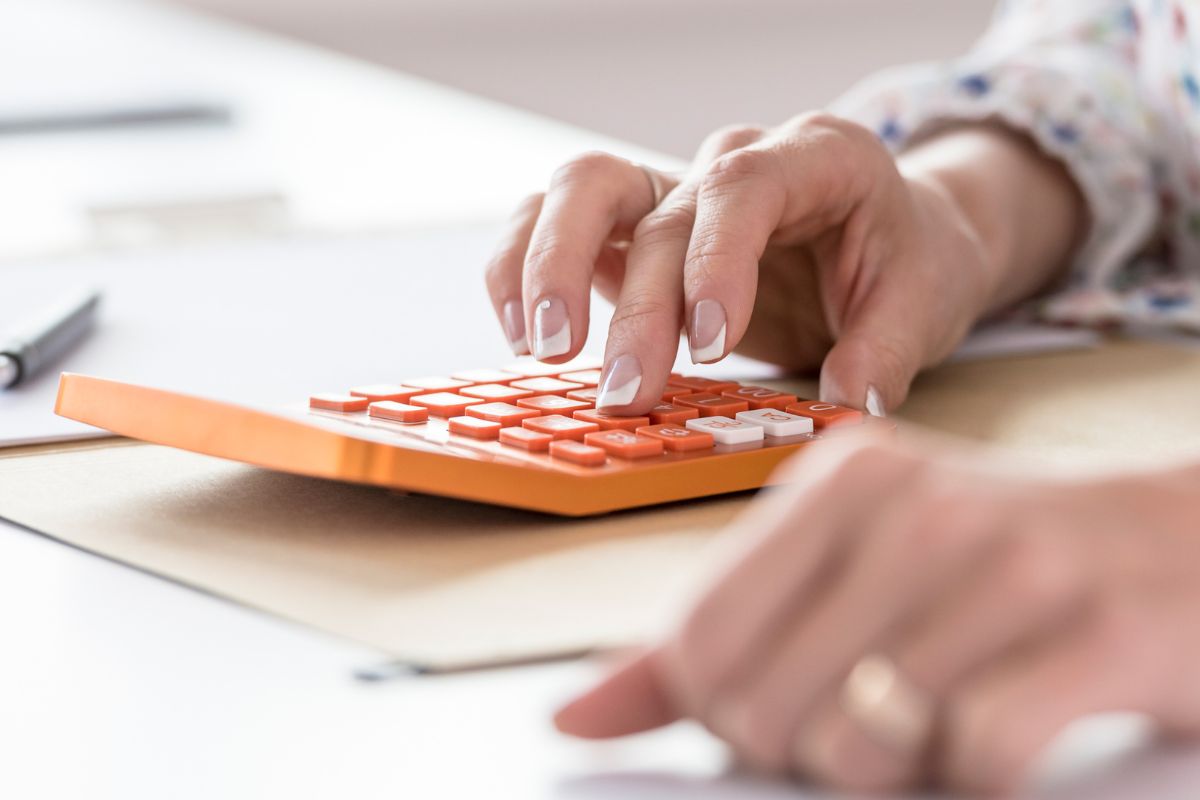 A woman's hand calculating her expenses.