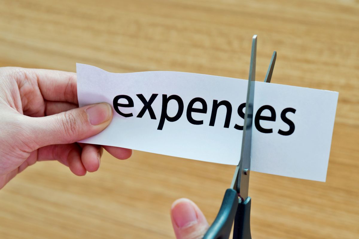 Image of a woman's hand cutting expenses.