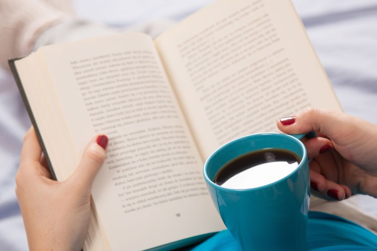 The image shows a woman's hand reading a book.