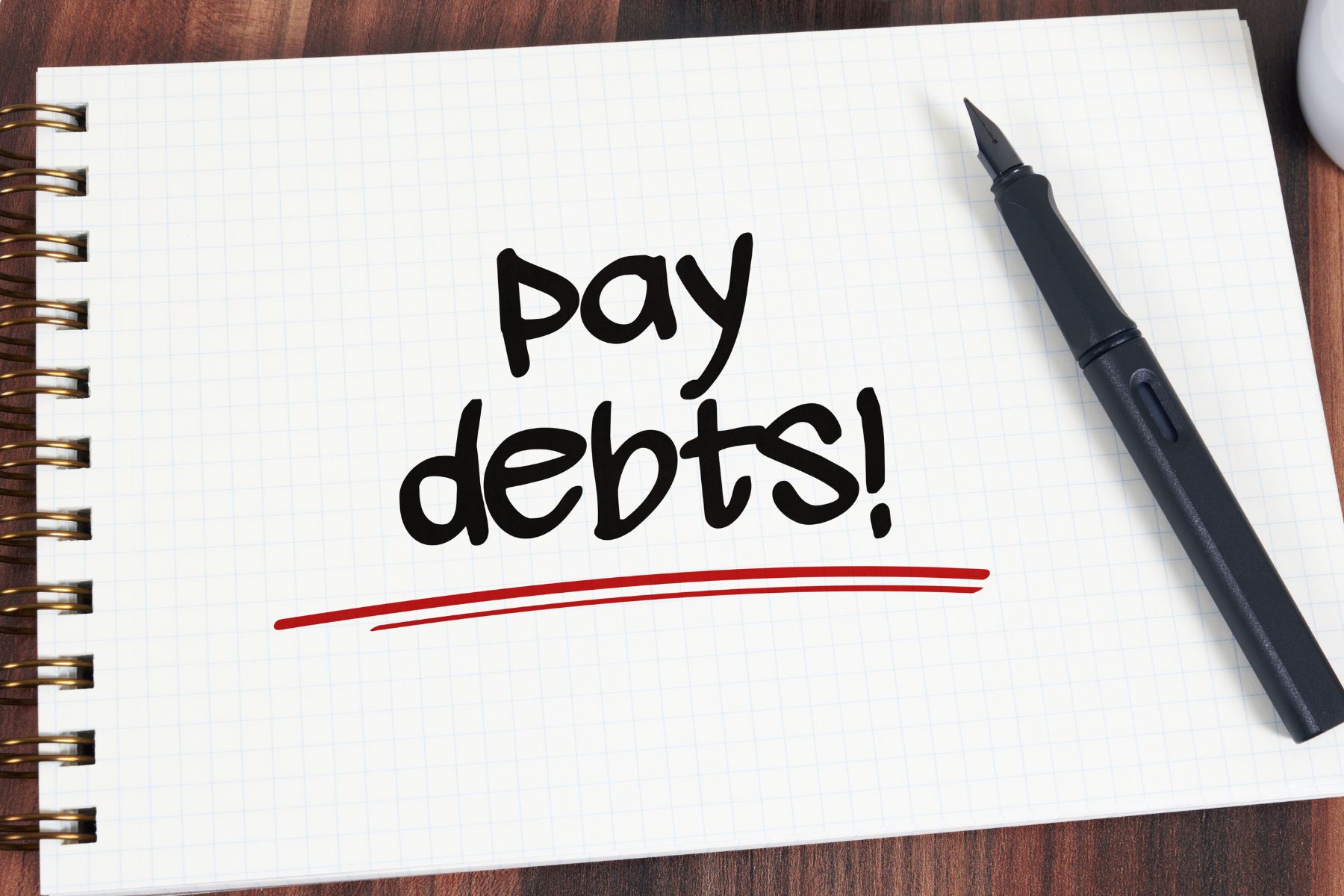 Image of a notebook with pay debt wording and a pen.