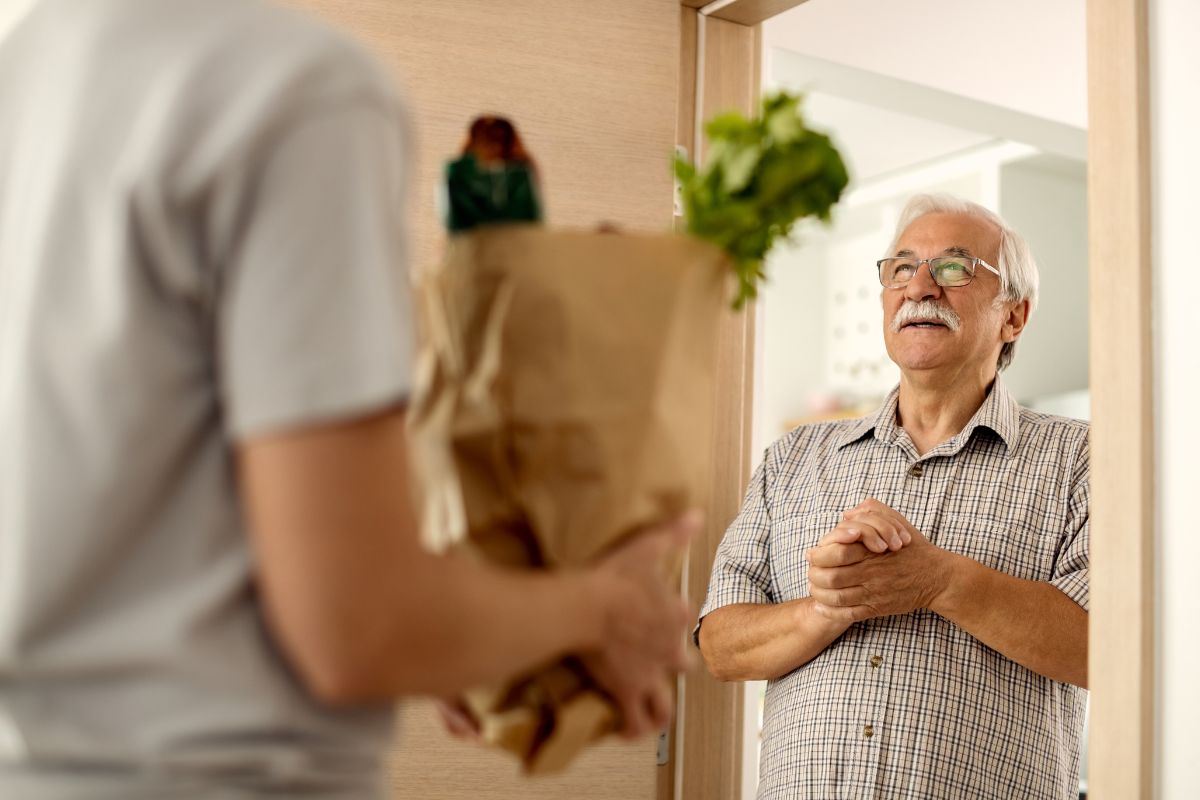 Photo of a man delivering a grocery to his neighbor.