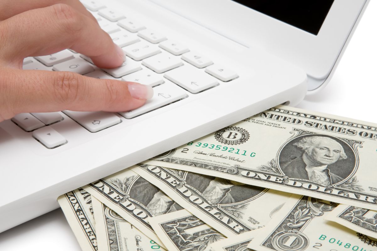 Picture of money and a woman's hand using a laptop.