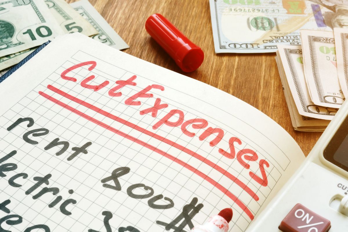 The picture shows a notebook with cut expenses wording.