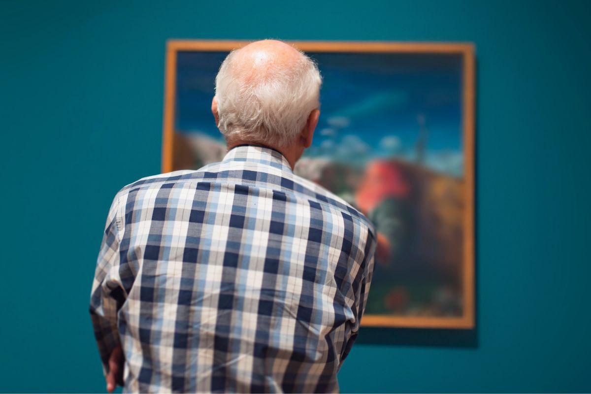 A senior man is staring at the painting.