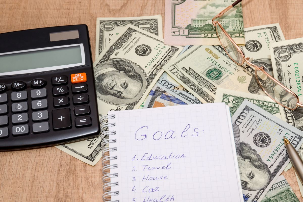 The picture shows money and a notebook with goals wording.
