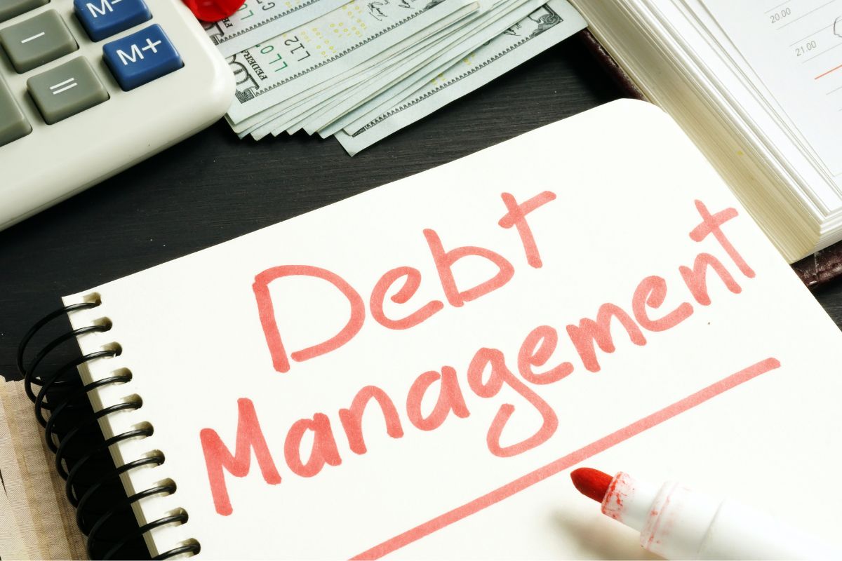 The photo shows a notebook with debt management wording.
