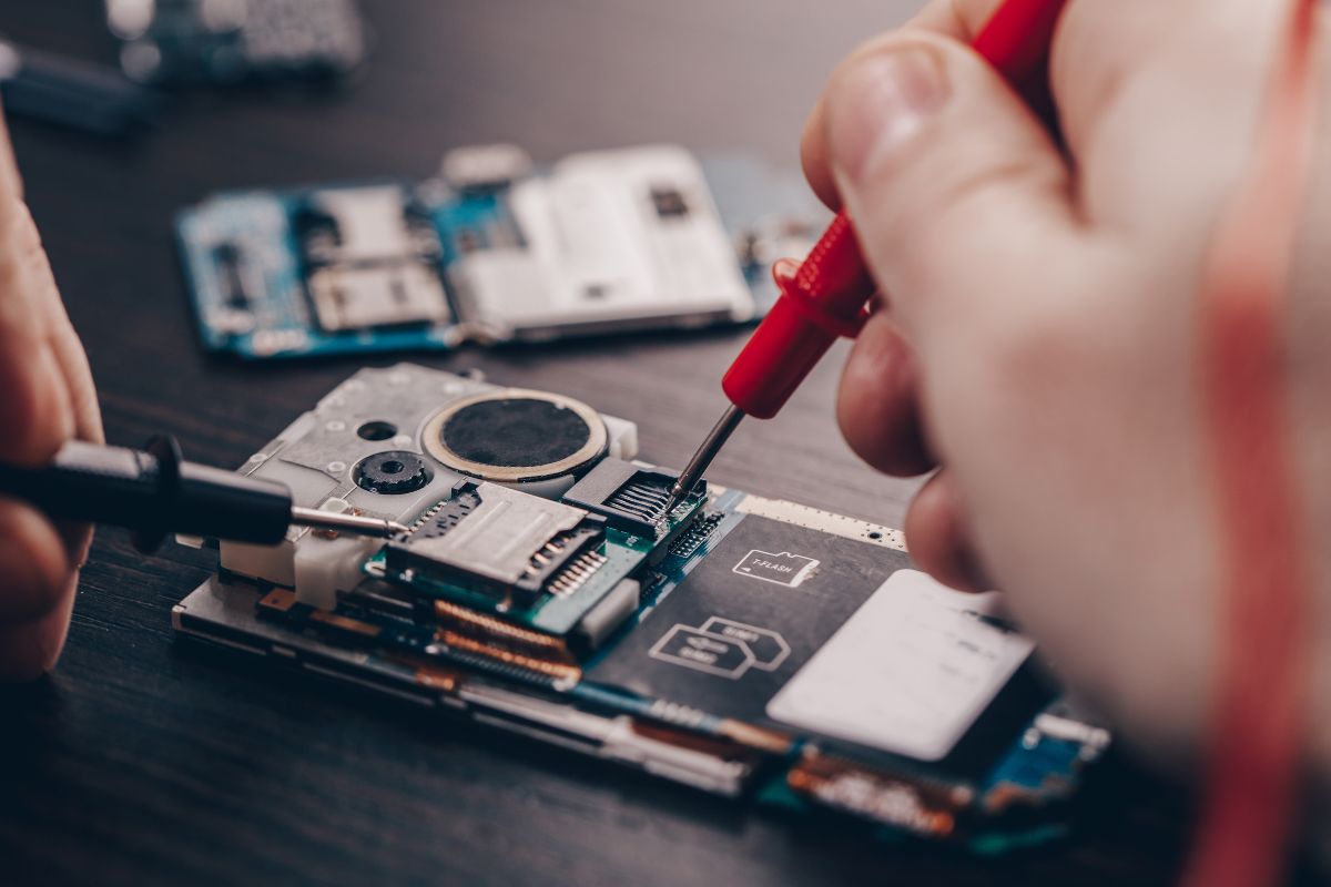 Picture of a man's hand repairing a phone.