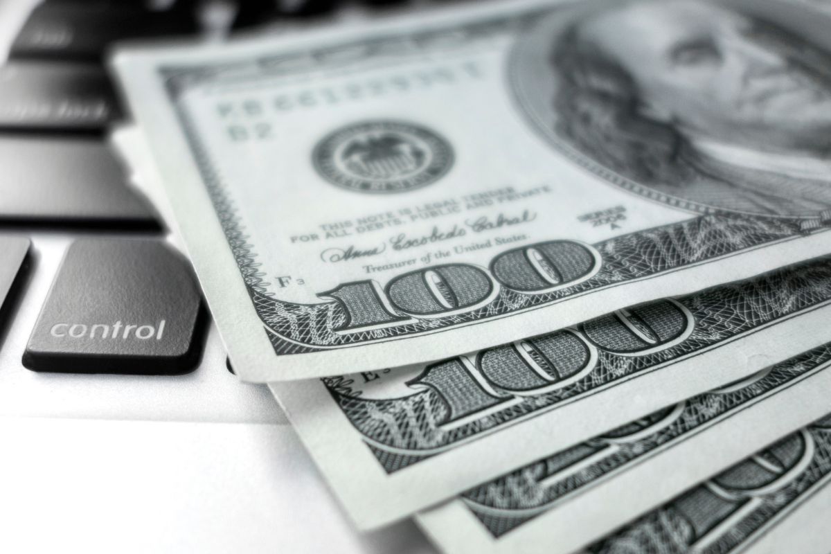 The photo shows a laptop and money.
