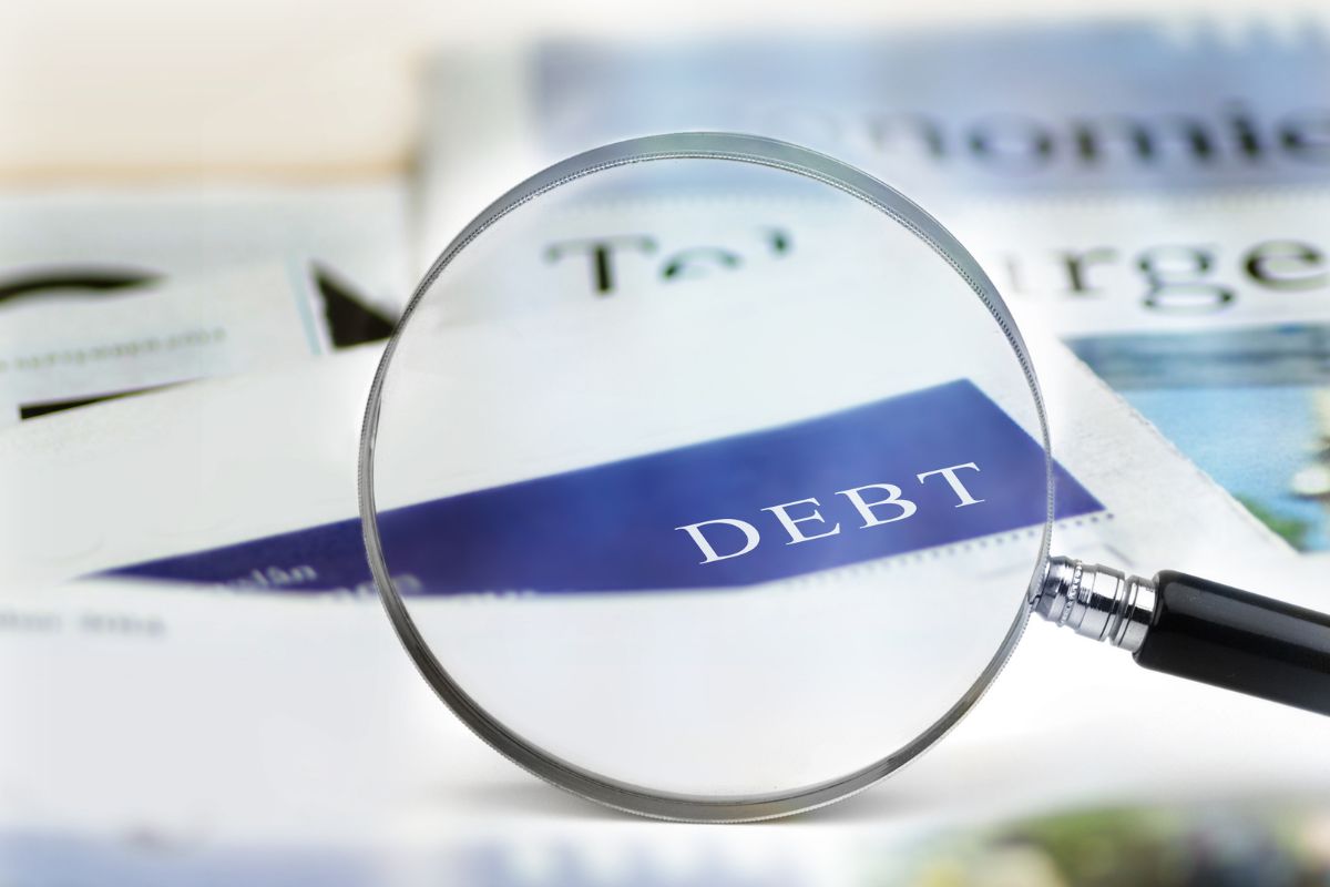 Photo of a magnifying glass and a debt paper.
