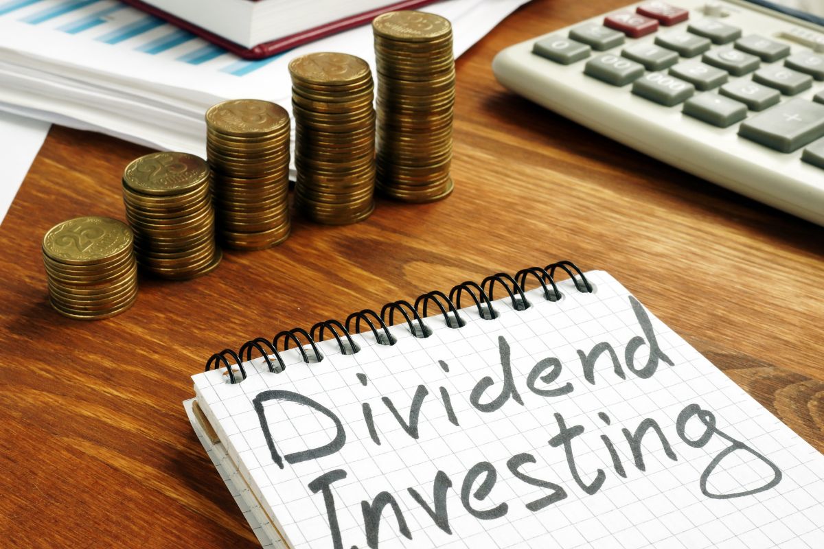 Photo of coins and a notebook with dividend investing wording.