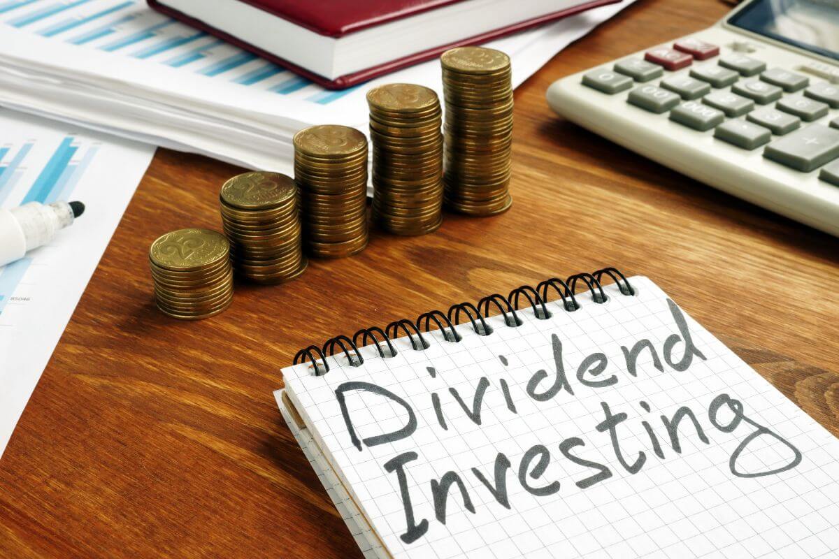 The photo tells about coin stocks, a calculator, papers, and a notebook with notes referring to investing in income-generating assets to keep your wealth growing while funding your lifestyle.