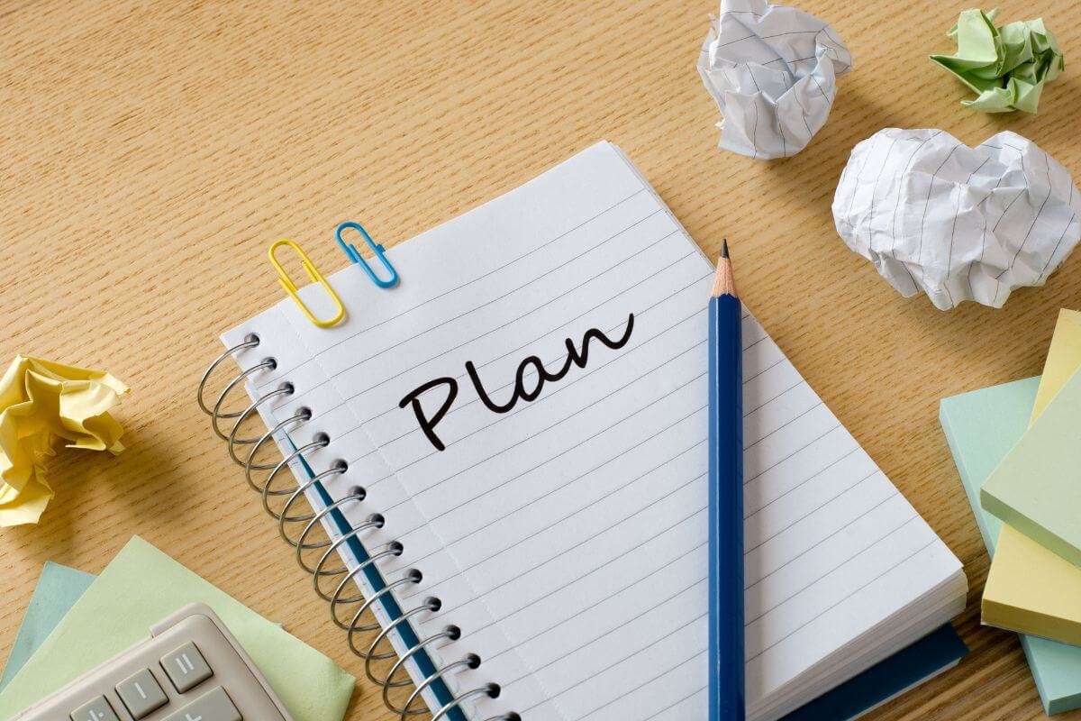 The picture of crumpled papers, a calculator, sticker notes, a pen, and a notebook with a note referring to building a legacy plan to pass on wealth or monitoring loved ones in financial literacy.