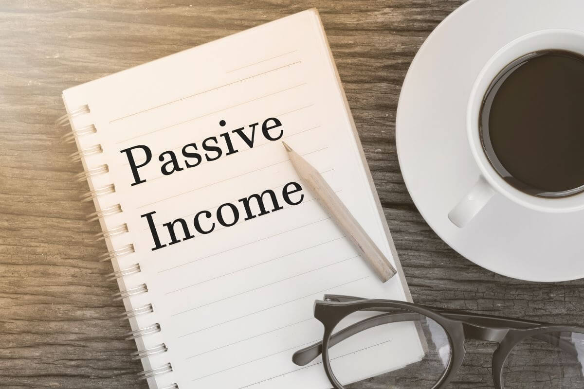 The photo shows a coffee, an eyeglass, a pen, and a notebook with notes indicating how to maintain and grow multiple streams of passive income to support your lifestyle.
