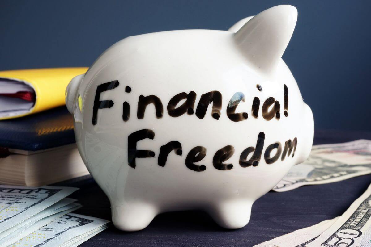 The picture shows dollars on the table, books, and a piggy bank with notes referring to enjoying financial freedom and achieving the financial independence you've worked so hard for.