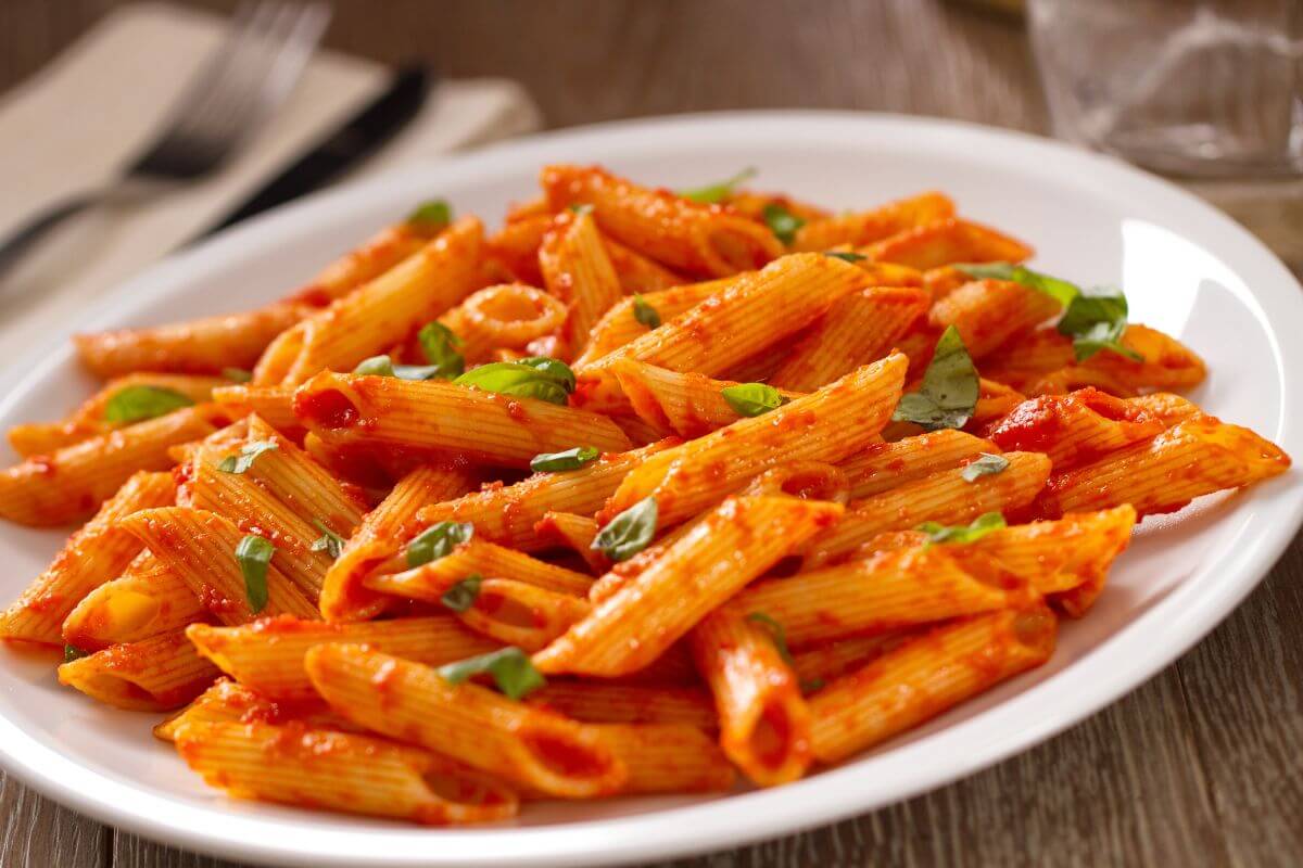 The photo tells about a pasta with tomato sauce and leaves indicating which perfect for frugal living and saving on groceries.