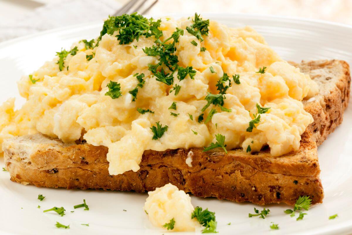 The photo of a toasted bread with scrambled egg and parsley at the top which are an affordable, protein-packed meal that's easy to make.