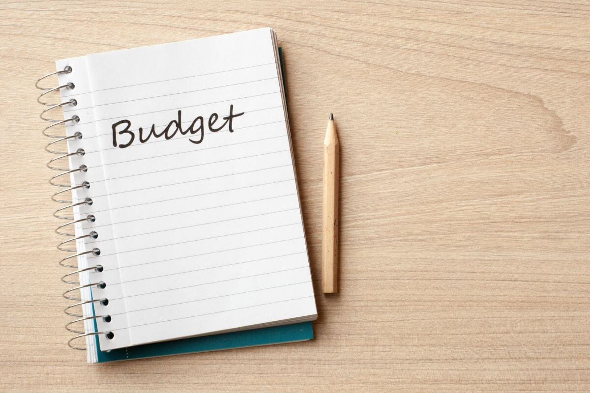 The photo tells about a pen and a notebook with a note referring to creating a minimalist budget to work toward financial independence.