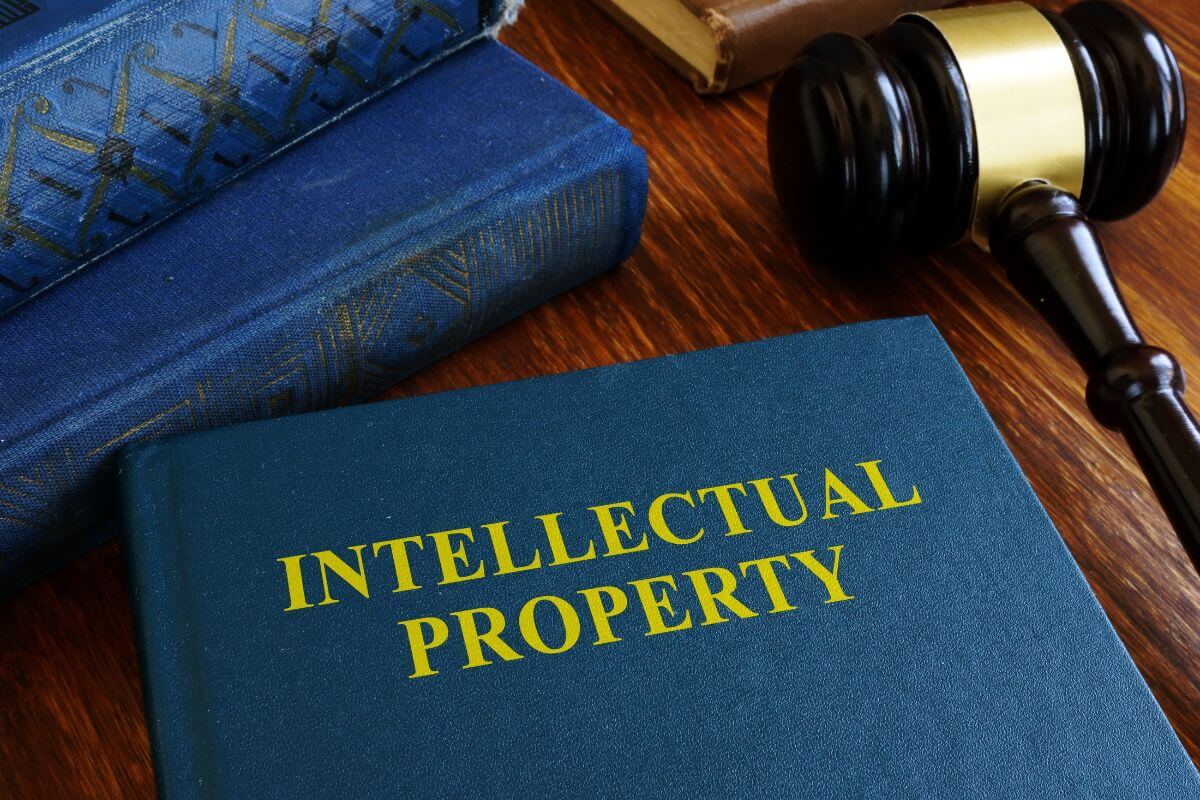 The photo of a book on the table, a gavel, and a book with a cover of notes indicate to creating and monetizing intellectual property becoming valuable long-term income sources.