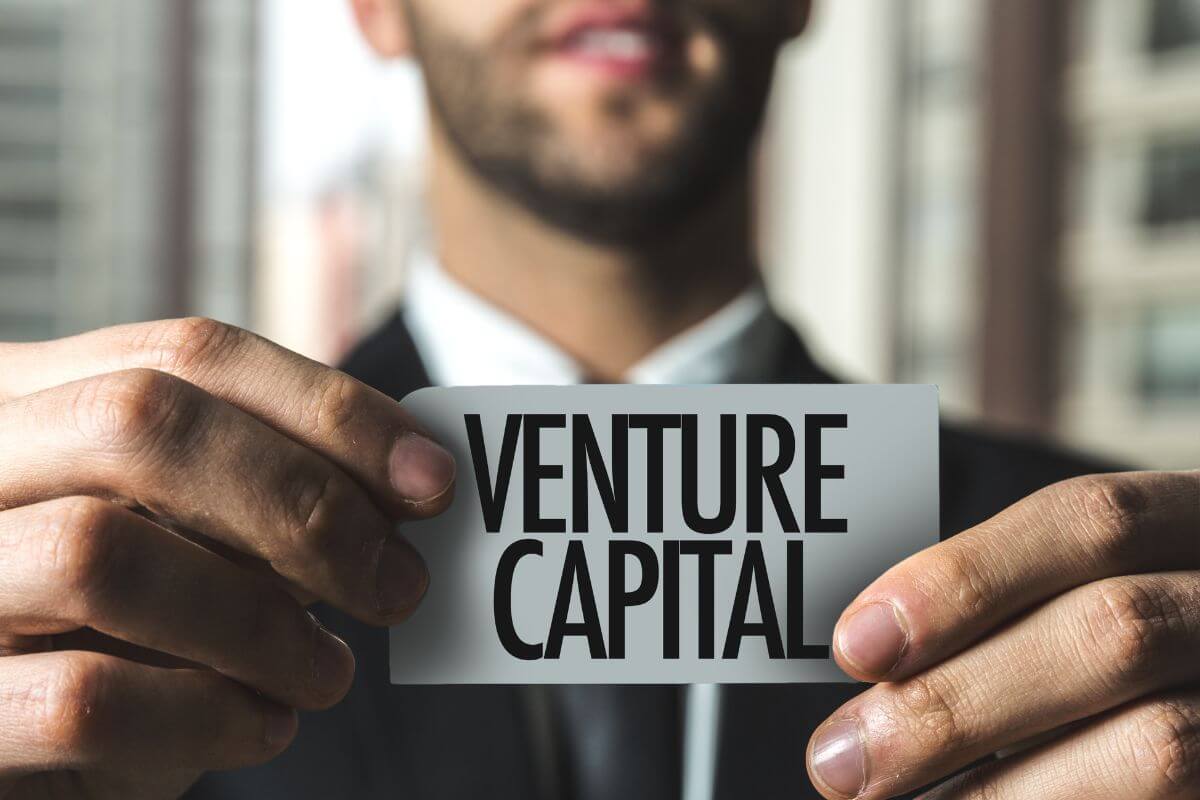 The picture of the man in a suit holding a piece of paper with notes which refers to partnering in venture capital can yield high returns when the business succeed.