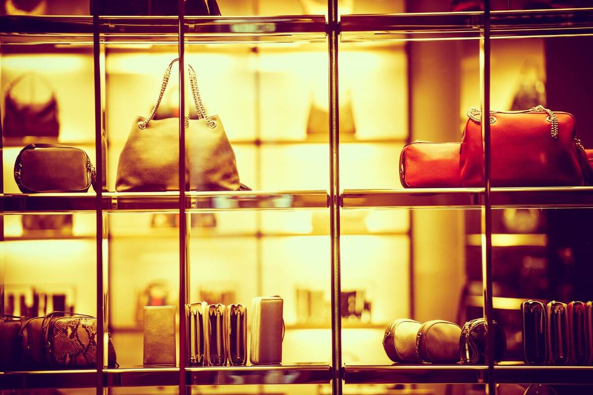 The phot tells about a rack with expensive bags displayed which means selling high-value products maximizes profits and builds wealth.