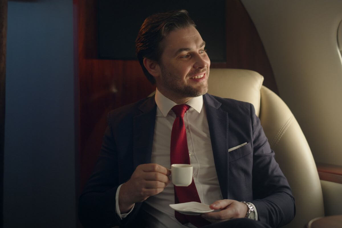 The photo of a man in a suit having a coffee inside a private jet refers to the next millionaire with these strategies toward financial independence and wealth creation.