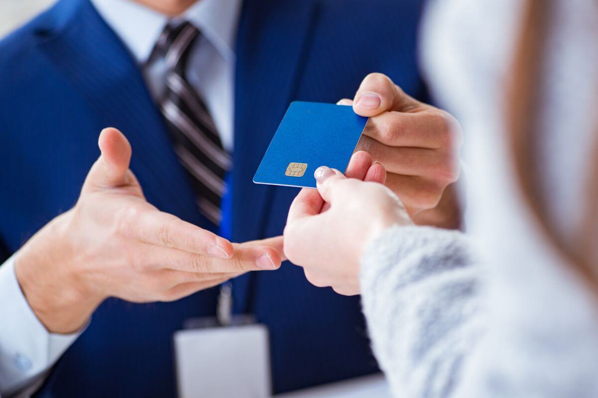 The picture tells about a customer's hand giving her credit card to the cashier who's hand taking it which means relying too heavily on credit cards can lead to trouble fast and creates a cycle of debt.