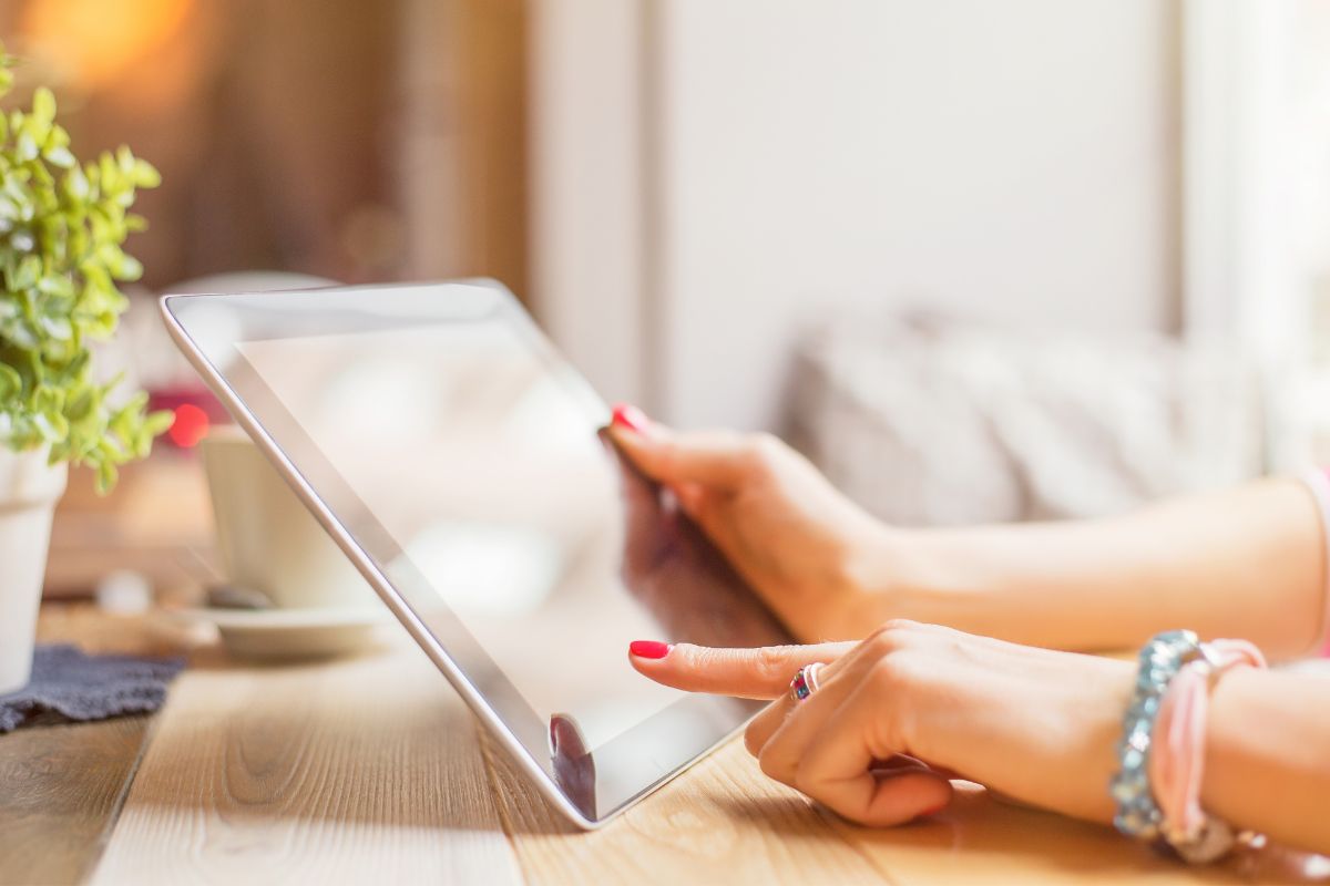 Image of a woman's hand using a tablet device.