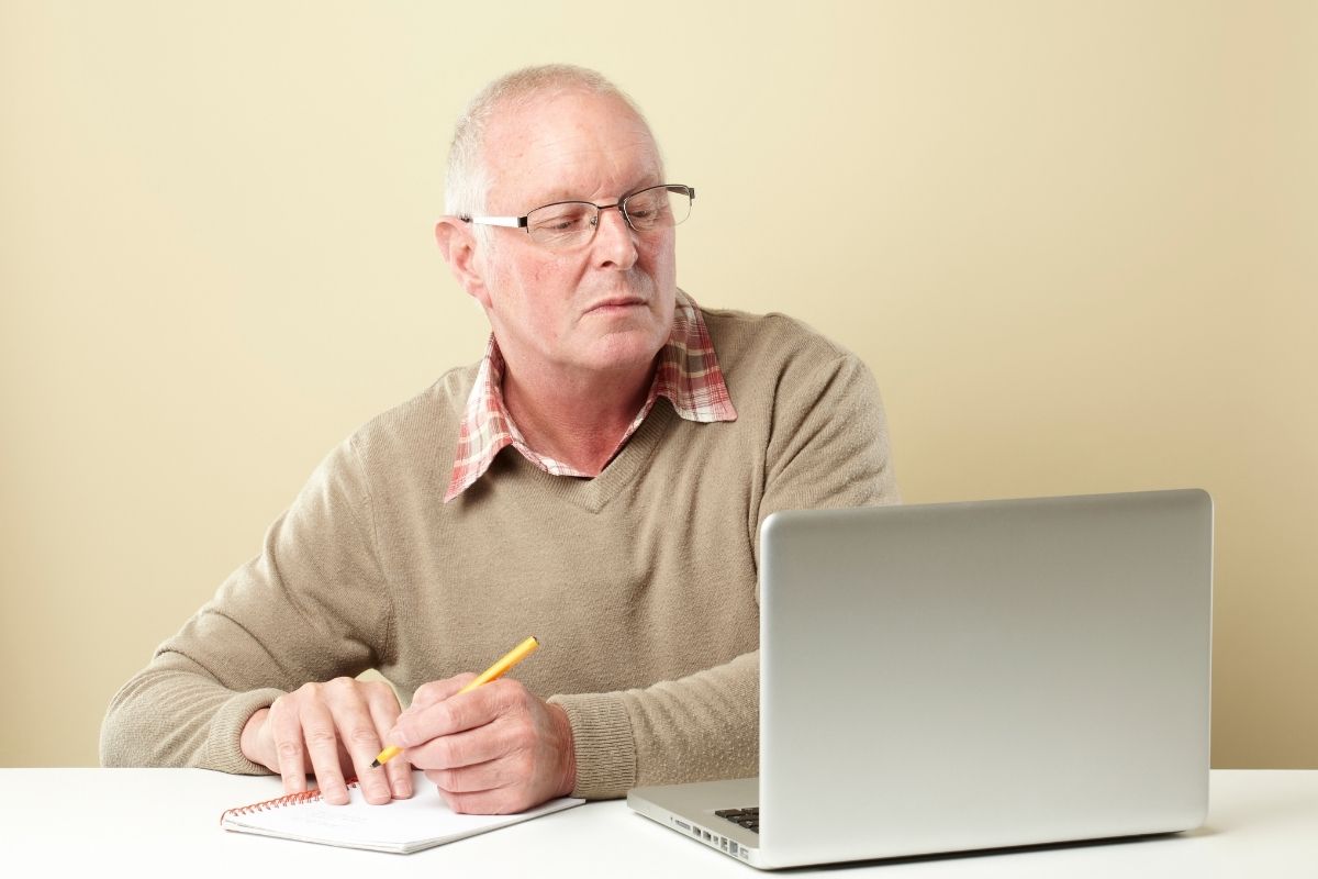 A senior man jotting down notes.