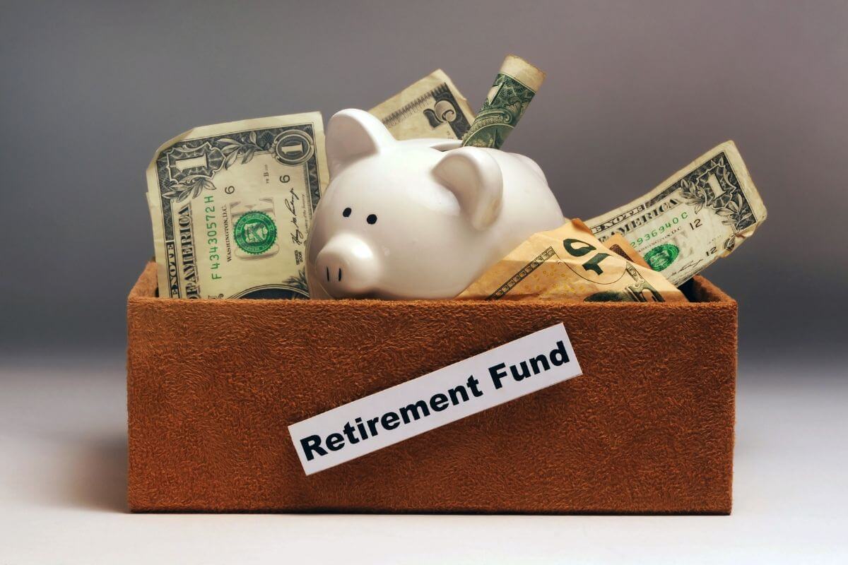 The picture of a wooden container with piggy bank and dollar bills and notes which refers to automate monthly contributions to your retirement fund which takes the stress out of remembering to save and builds your funds over time.