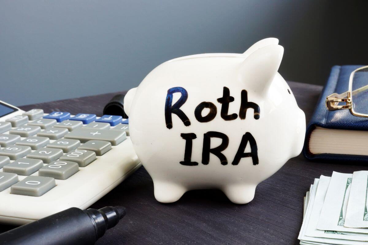 The picture shows a calculator, a notebook, an eyeglass, dollar bills, and a piggy bank with notes which means to consider a Roth IRA that helps your tax rate to be higher later.