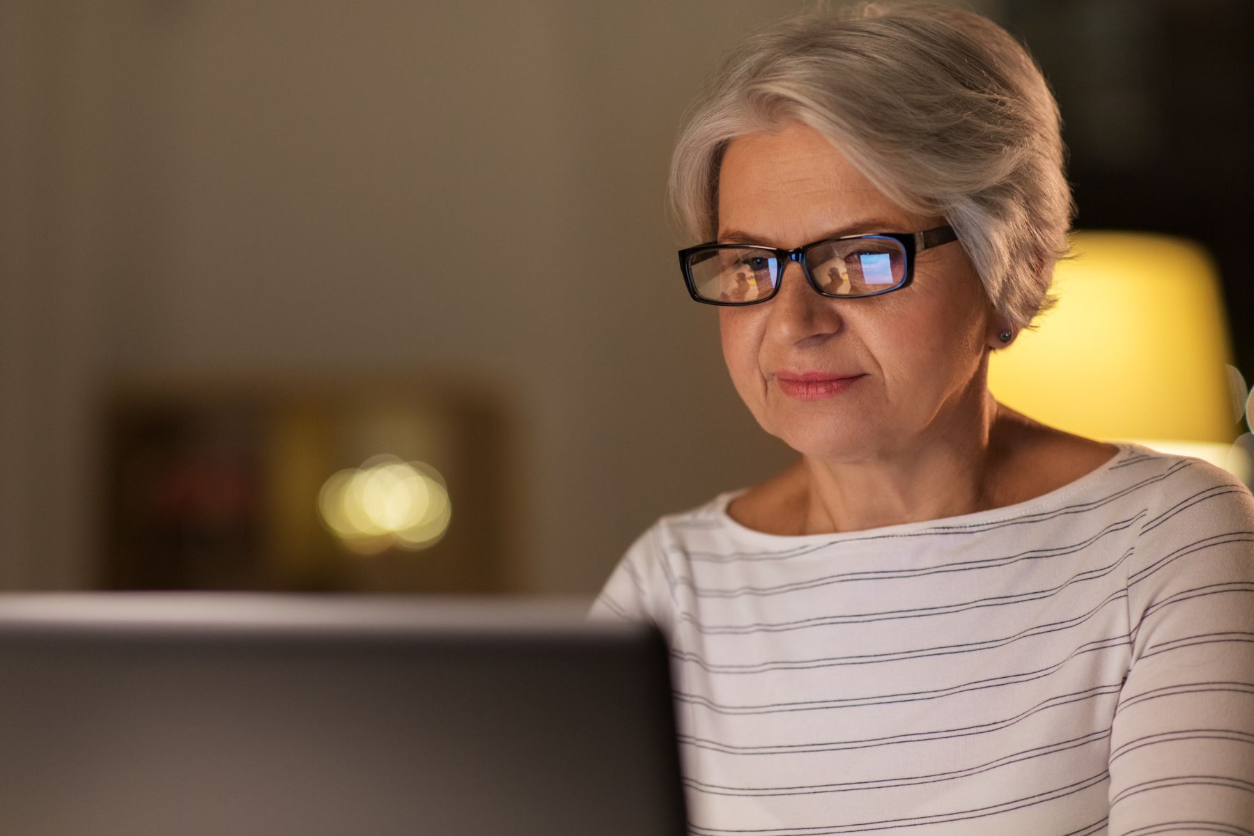 The image of a senior woman using a laptop.